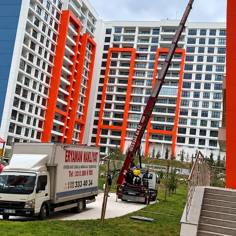 Apartmanların önündeki Eryaman Nakliyat kamyonu ve binaya uzanan taşıma asansörü