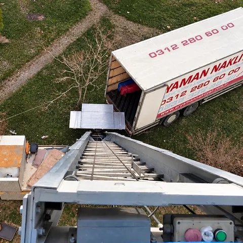 Yukarıdan görülen taşıma asansörü ve arka kapısı açık Eryaman Nakliyat kamyonu