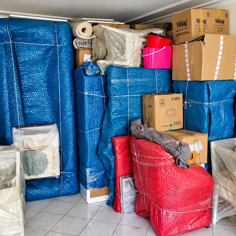 Mavi ve kırmızı ambalajlarla sarılmış mobilyalar, sandalyeler ve koliler