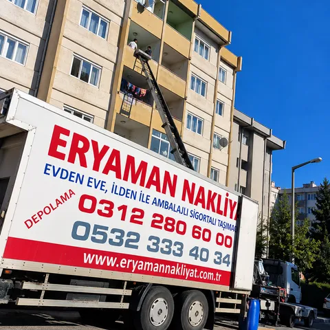 Apartman balkonuna uzanan taşıma asansörü ve Eryaman Nakliyat kamyonu