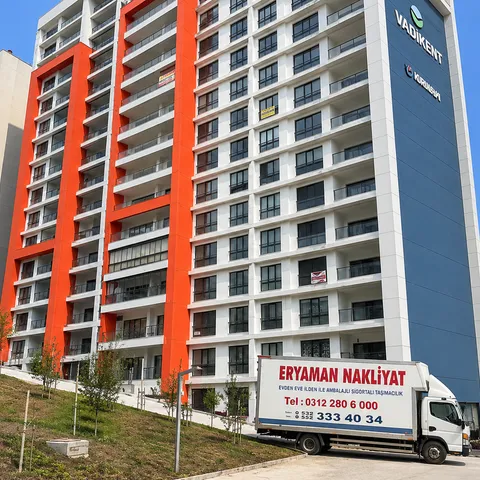 Yüksek apartmanların önünde park edilmiş Eryaman Nakliyat kamyonu